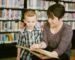 Frau und Kind betrachten gemeinsam ein aufgeschlagenes Buch in einer Bibliothek